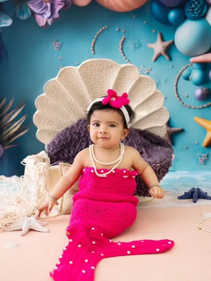 A beautiful portrait of our little mermaid. The vibrant colors of the outfit and the underwater-themed backdrop make this a stunning milestone photo.