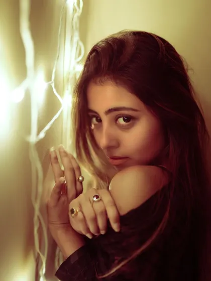 A close-up portrait with fairy lights creating a beautiful bokeh effect. The focus is on the model's expressive eyes.
