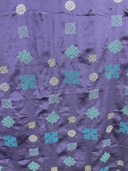 A close-up of the contemporary Kasuti embroidery on the navy blue silk. The different shades of blue thread add depth and movement to the geometric patterns.