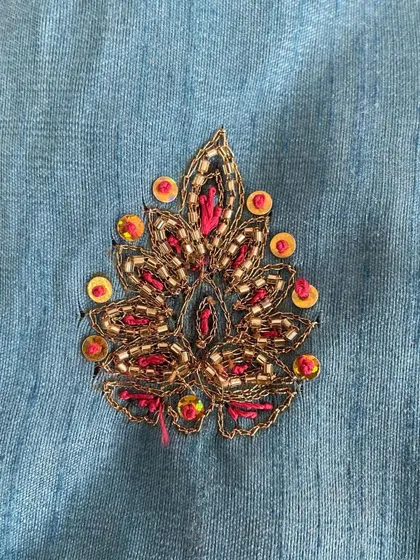 A floral motif combining Zari threadwork, beads, and sequins. This mix of materials adds texture and a rich, festive look to the embroidery.