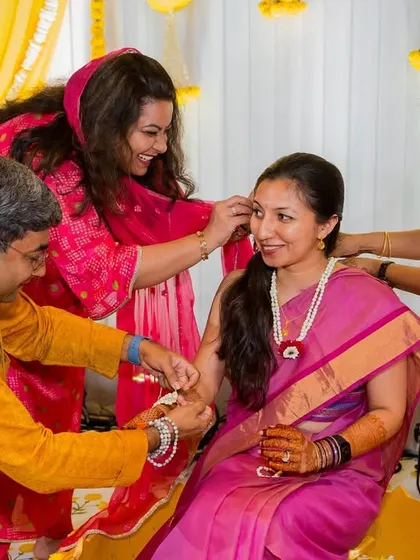 Family members come together to adorn the bride with floral jewellery during a pre-wedding ritual, a moment full of love and tradition.