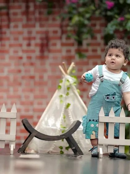 A little boy playing in our garden with a white picket fence and teepee. We have many props to create a fun and engaging environment.