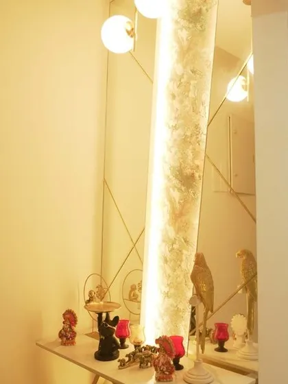 A beautifully lit console table in the foyer, featuring a decorative mirror and alabaster-style paneling. This elegant setup creates a warm and welcoming first impression.