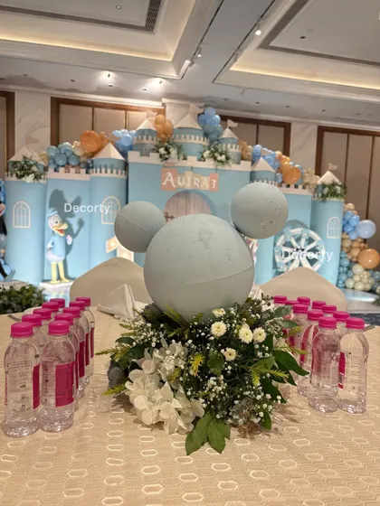 A Mickey Mouse-shaped floral centerpiece on a guest table, with the grand castle stage visible in the background.