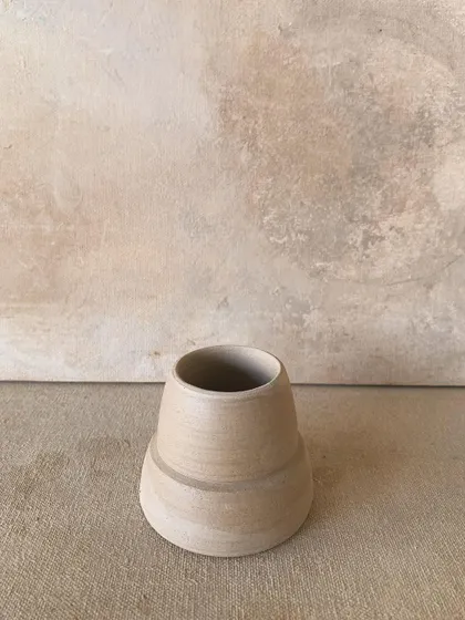 A raw, unglazed vase with a simple, elegant form.