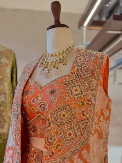 A detailed shot of the peach brocade jacket, highlighting the intricate weaving and sequin embellishments that make it a true work of art.