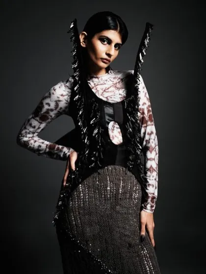 This look for a designer editorial features dramatic, dark eye makeup and a sleek, center-parted hairstyle. The entire look is built to complement the futuristic, structured fashion piece.