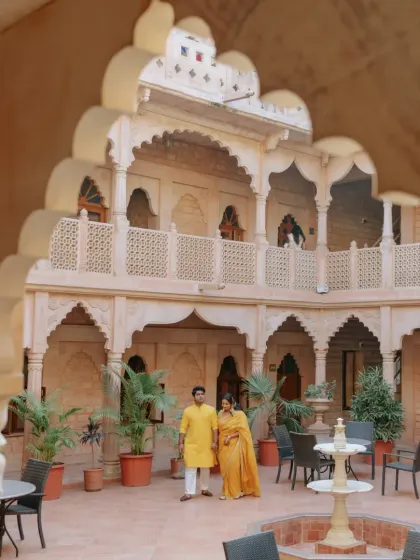 The couple posing in the beautiful courtyard of the Rajasthan palace during their Haldi celebrations.
