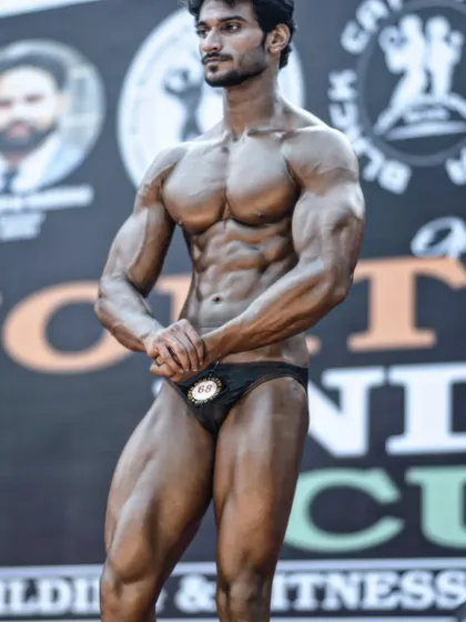 A front pose on stage, showing the v-taper and abdominal definition. This is the aesthetic I help my clients work towards.