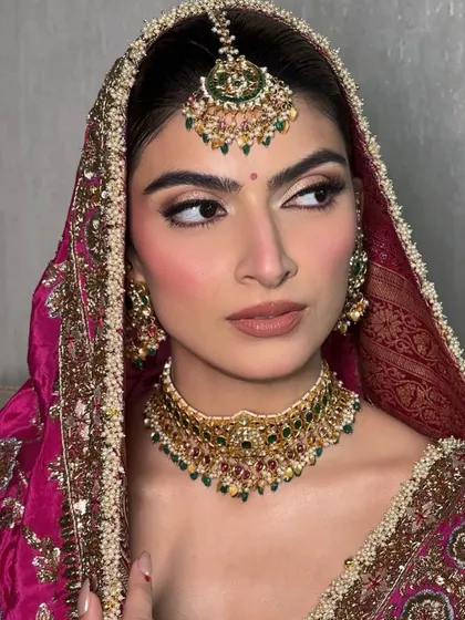 A close-up portrait of Seher for her wedding day. The makeup is classic and defined, with a sharp winged liner that accentuates her beautiful eyes, paired with a traditional pink outfit.