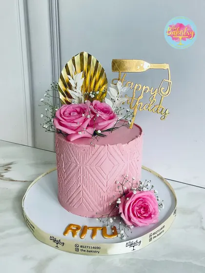 An elegant pink cake for Ritu's birthday, adorned with delicate roses, a touch of gold, and a modern textured pattern.