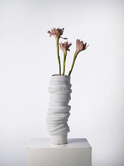 With its wrapped, textured surface, this white ceramic vase evokes the feeling of hand-spun textiles. It is a perfect example of how we use texture to add depth and warmth to minimalist forms.