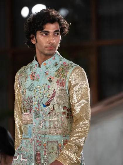 This is a truly special piece. A bandhgala jacket featuring a story-telling landscape embroidered with peacocks and palaces, paired with shimmering gold sequin sleeves for a modern twist.