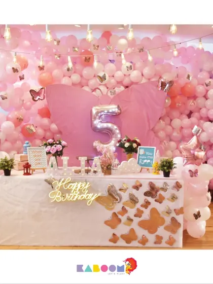 A beautiful butterfly-themed party, surrounded by a sea of pink and white balloons. The golden butterflies on the table add a touch of elegance.