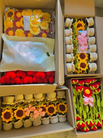 An overhead view of four open boxes, filled with a large wholesale order of potted sunflowers, hearts, and stems.
