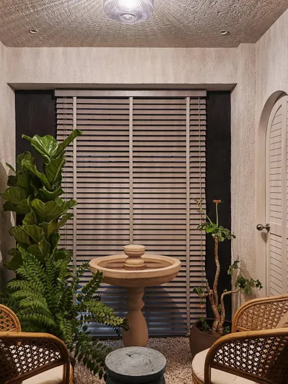 The fountain area, accessible from the kitchen, is a small, Zen-inspired courtyard. A stone fountain sits on a bed of white gravel, surrounded by plants, creating a perfect spot for quiet contemplation.