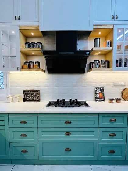 A full view of the two-toned kitchen, highlighting the balance between the sea-green lower cabinets and the white upper cabinets. The black chimney acts as a modern focal point.