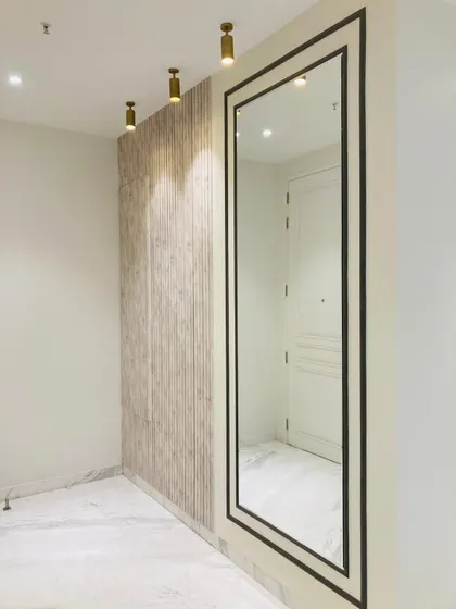 A full-length mirror with a bold black frame is paired with a wood-paneled wall and spotlights. This combination not only makes the entryway feel larger but also adds a touch of drama and sophistication.