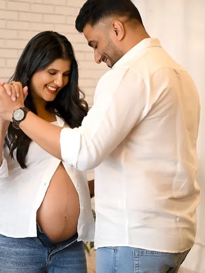 A joyful and candid maternity shot of a couple dancing together in the studio. Their smiles capture the happiness of this special journey.