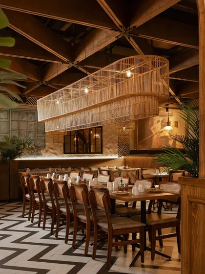 A large, custom-made cane light fixture hangs over the main dining area, creating a dramatic focal point.