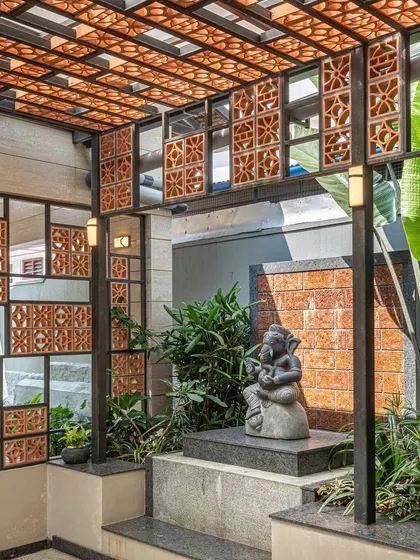 We created this sacred puja corner as a peaceful alcove. The Ganesha statue is nestled among plants and framed by a custom terracotta and glass jaali screen, which filters light and adds a layer of intricate detail.