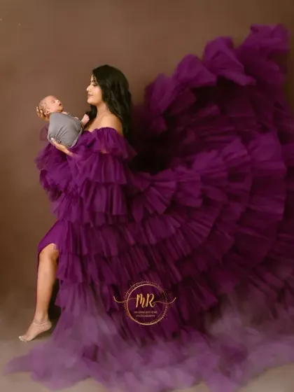 A creative and artistic portrait of a mother holding her newborn. The flowing purple gown and dreamy, cloud-like effect create a magical, ethereal scene.