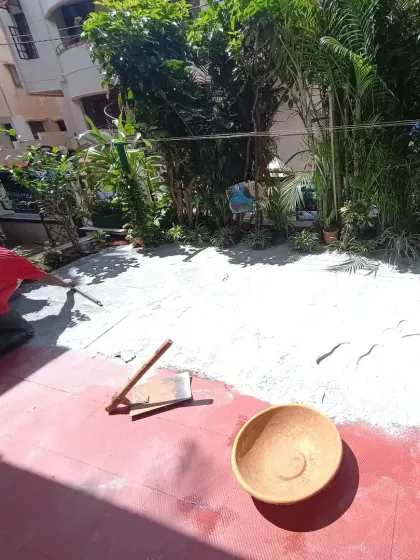 Smoothing the base layer in a garden setting, working carefully around the existing tiled patio.