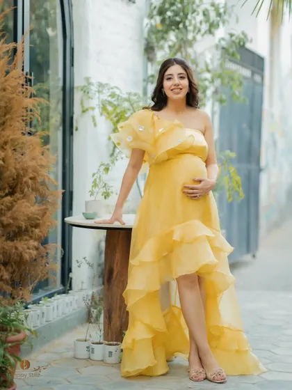 A full-length portrait of the mom-to-be at her "ray of sunshine" themed baby shower. She looks serene and beautiful.