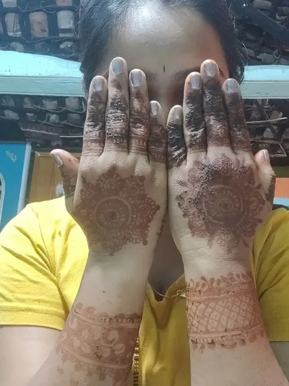 A client showing the back of her hands, with a simple and beautiful mandala design.