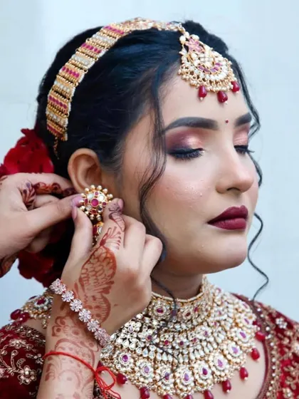 The final touches are what bring the entire bridal look together. Here, I'm placing the jewelry on my bride, whose makeup features a stunning cranberry smokey eye and a deep red lip.