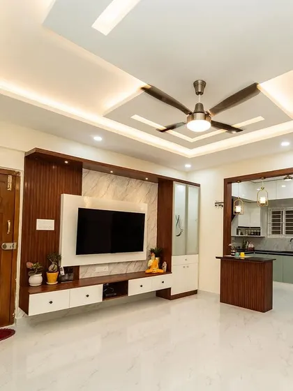 An open-plan layout where the living area seamlessly connects to the kitchen. The consistent use of wood and white cabinetry, along with a stylish breakfast counter, unites the two zones.