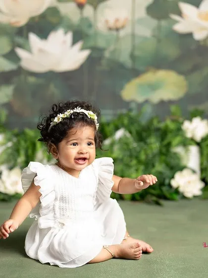 A moment of quiet contemplation from this sweet baby girl. The simple white dress and the beautiful lotus pond backdrop create a serene and artistic portrait.