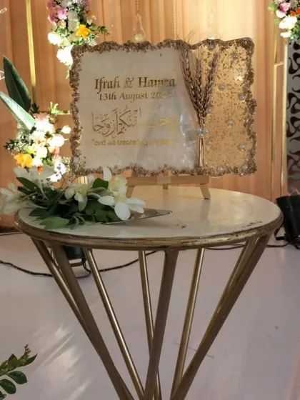 A custom-made, ornate resin art piece with the couple's names and wedding date, serving as a unique and personal decor element.