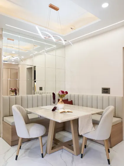 Adjacent to the kitchen is this cozy dining nook with beige upholstered bench seating and a modern pendant light. The mirrored wall helps to visually expand the space.