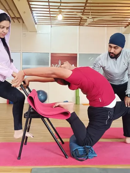 For many, deep backbends seem impossible due to stiffness or fear of injury. Here, I am assisting a student using a yoga chair for support, allowing them to safely open their spine and build confidence. My one-on-one therapeutic approach ensures that every pose is adapted to your body's specific needs.