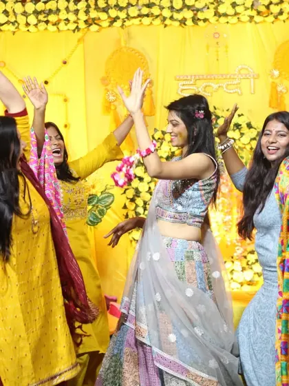 The Haldi ceremony is all about high energy and celebration. This action shot captures the bride-to-be and her friends dancing with their hands in the air, surrounded by festive yellow decor.