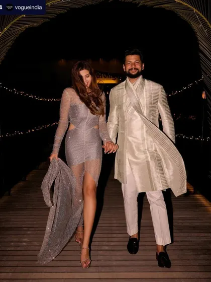A candid shot of the couple from their Vogue-featured wedding. Her sparkling after-party dress is paired with a relaxed yet glamorous hair and makeup look.