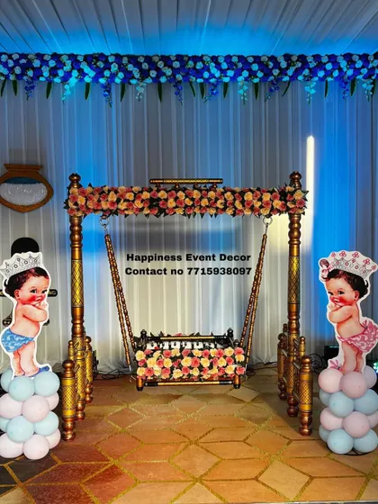 A simple and elegant naming ceremony setup with a flower-decorated Sankheda jhula. The baby prince and princess cutouts on either side add a royal touch to the occasion.