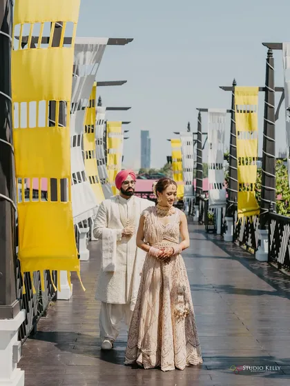 A full-length portrait of the couple on a bridge in Bangkok, their elegant outfits complementing the modern, clean lines of the location.