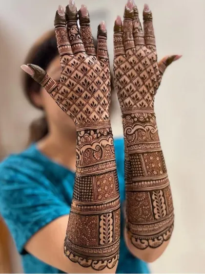 A full-sleeve bridal mehandi with a focus on intricate jaali work on the palms and detailed bands on the arms.