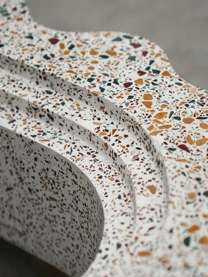 A close-up of the flowing curves on our custom terrazzo bookshelf. The smooth, polished surface highlights the colorful aggregate mix within the sculptural form.
