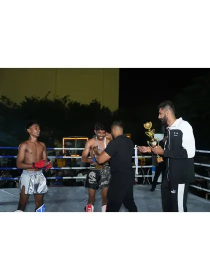 Awarding a trophy to a victorious fighter in the ring. Recognizing the hard work and success of our athletes is a key part of our culture.