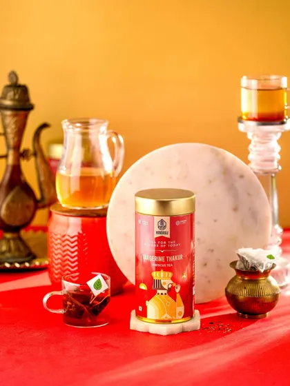 A vibrant and regal shot of Hindraj's Tangerine Thakur Tea. The bold red and gold color scheme gives the product a luxurious and festive feel, perfect for a special occasion.