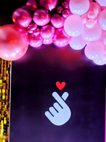 A close-up of the Blackpink party decor, showing the iconic finger heart symbol against a black panel.