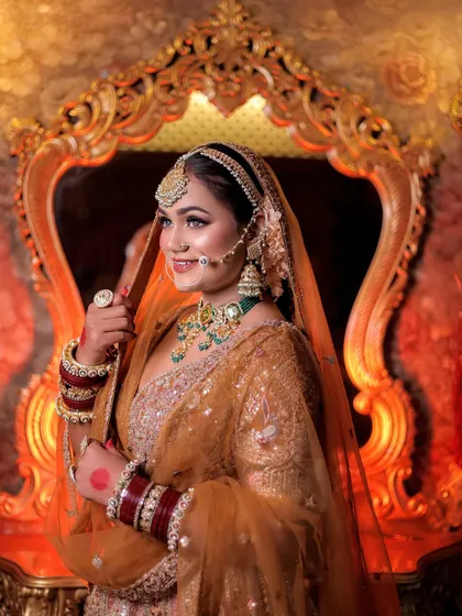 A beautiful portrait of the bride smiling, framed by the ornate golden mirror. The warm backlighting creates a halo effect, enhancing her bridal glow.