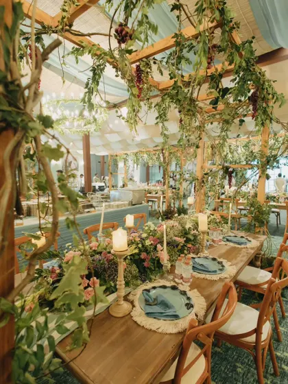 An enchanting dining setup under a canopy of vines and flowers. I love creating magical settings that transport guests to another world.