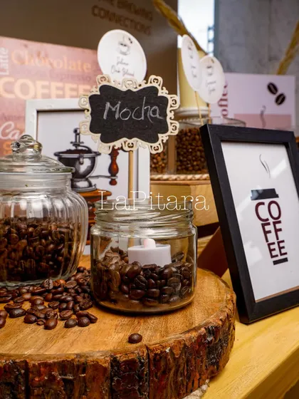A close-up of the small details that bring a theme to life. A jar of coffee beans with an electric candle, a chalkboard "Mocha" sign, and framed coffee art contribute to the rich, layered decor.