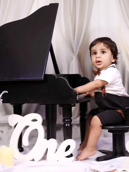 A little boy looking sharp and ready to play the piano for his first birthday photos.
