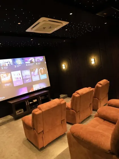 This wide-angle shot captures the full beauty of the room, from the starlit ceiling to the comfortable recliners and the large, vibrant screen.