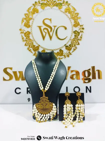 A new design that combines the beauty of floral jewellery with a traditional golden pendant. This elegant necklace and jhumka set can enhance any festive look.